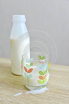 Milk bottle, a partial filled glass and spilt milk