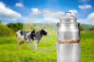 Milk can against cow pasture meadow