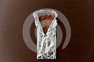 Milk chocolate bar with nuts in foil wrapper