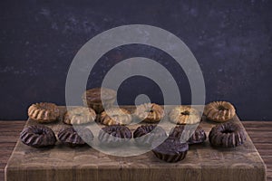 Milk and chocolate muffins on a wooden board in the form of a checkerboard on an abstract blue background