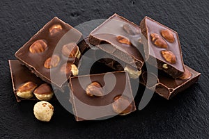 Milk chocolate pieces with nuts on a dark background