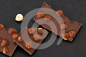 Milk chocolate pieces with nuts on a dark background