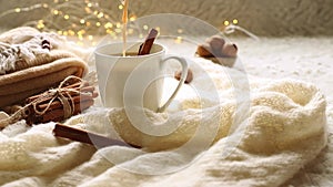 milk , coffee, cacao or hot chocolate puring into a white mug, scandinavian style cozy morning with some knitted