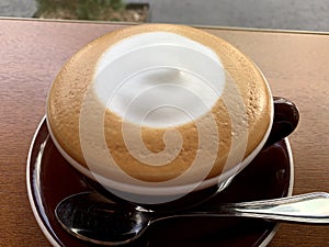 Milk coffee with cream in the middle in a white cup