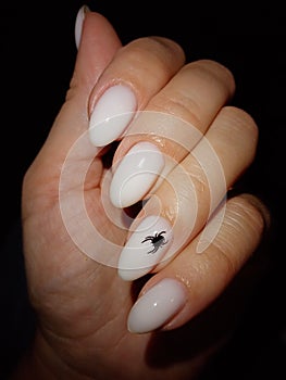 Milk-colored nail design. A spider on the leg. Manicure. Female fingers