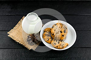 Milk, cookies on a black textured wooden table. Rustic background.
