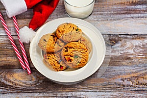 Milk and cookies for Santa Claus and Santa`s hat over wooden bac