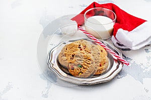 Milk and cookies for Santa Claus and Santa`s hat over wooden bac