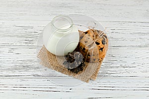 Milk, cookies on a white textured wooden table. Rustic background.