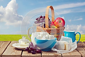 Milk, cottage cheese, butter and fruit basket over meadow background. Jewish holiday Shavuot celebration photo