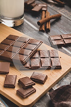 Milk dark chocolate tiles on wood cutting board, wooden background