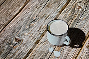 Milk in an enameled light blue mug on a rough wooden table