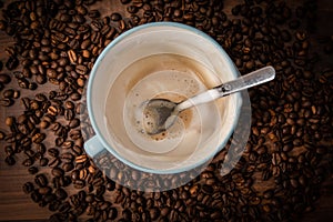 Milk foam and a spoon in a coffee cup. Coffee beans background