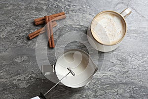 Milk frother over pitcher near cup of coffee photo