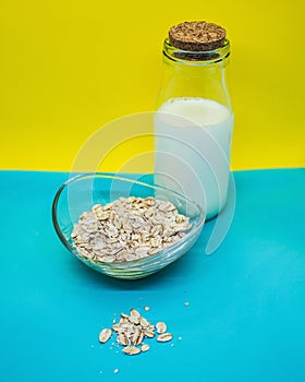 Milk in a glass bottle and oatmeal on a bright background.