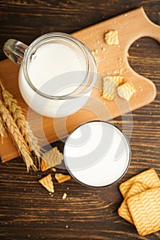 Milk in glass and jug with cookie on wooden table on a grey background, close-up. Top view