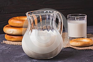 Milk in a glass jug with fresh bagels on the table