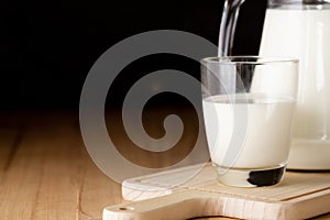 Milk in glass and jug on wooden table