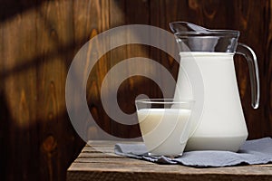 milk in glass and jug on wooden table