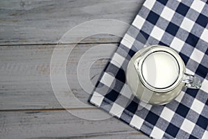 Milk in a glass jug on a wooden table, top view