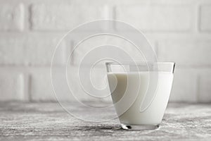 milk in glass on table with white brick wall as background