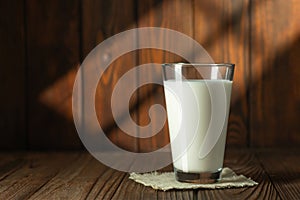 milk in glass on wooden table with sun rays