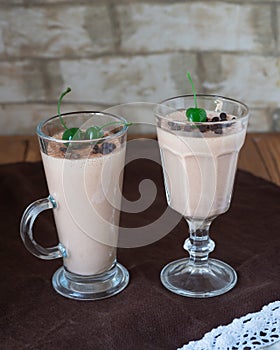 Milk iron with green puff, sprinkled with chocolate in two glass goblets on a table covered