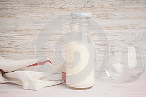 Milk in jar and glass on a light wooden background