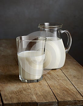 Milk jug and glass on wooden table