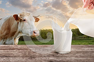 Milk from jug pouring into glass with splashes