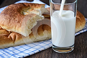 Milk is poured into a glass, bread on a kitchen towel