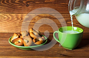 Milk is poured into a green mug. A plate of homemade bagels on vintage boards. Idea for a delicious festive breakfast or dinner