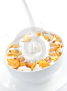 Milk pouring into a bowl of corn flakes photo