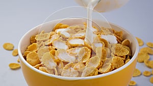 Milk pouring into bowl of corn flakes cereal