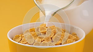 Milk pouring into bowl of corn flakes