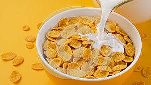 Milk pouring into bowl of corn flakes