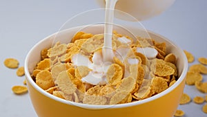 Milk pouring into bowl of corn flakes