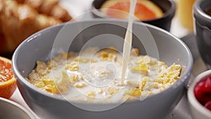 Milk pouring into bowl full of corn flakes with splashing. Healthy breakfast concept