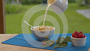 Milk pouring into a bowl with muesli