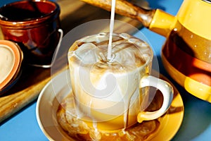 Milk pouring into a cold cup of iced coffee