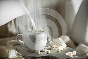 milk pouring from a jar into cup overt white morning natural background, breakfast meal at home or hotel