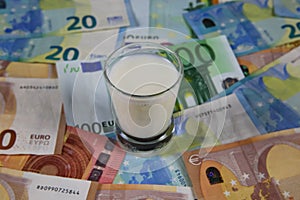 Milk price and agricultural products trend concept: Small glass of milk on euro money bank notes