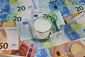 Milk price and agricultural products trend concept: Small glass of milk on euro money bank notes