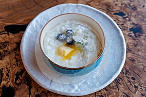 Milk rice porridge with blueberry, butter and mint leaf, creamy rice pudding or french riz au lait in a ceramic bowl on