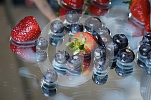 Milk splash close up of falling berries in a grey plate of milk. Blueberries and Strawberries multivitamin cocktail. Healthy diet.