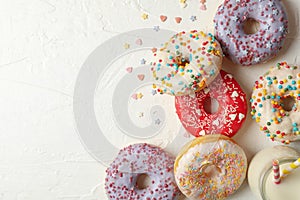 Milk and tasty donuts on white background,  top view