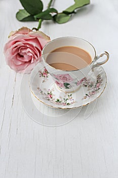 Milk tea in a china cup and saucer, with pink roses.