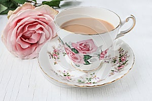 Milk tea in a china cup and saucer, with pink roses.