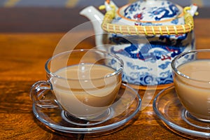 Milk Tea served in a glass cup and saucer on a wooden table