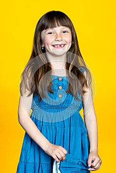 Milk teeth are replaced by permanent ones. A funny preschooler girl smiles broadly, there are no front teeth in her